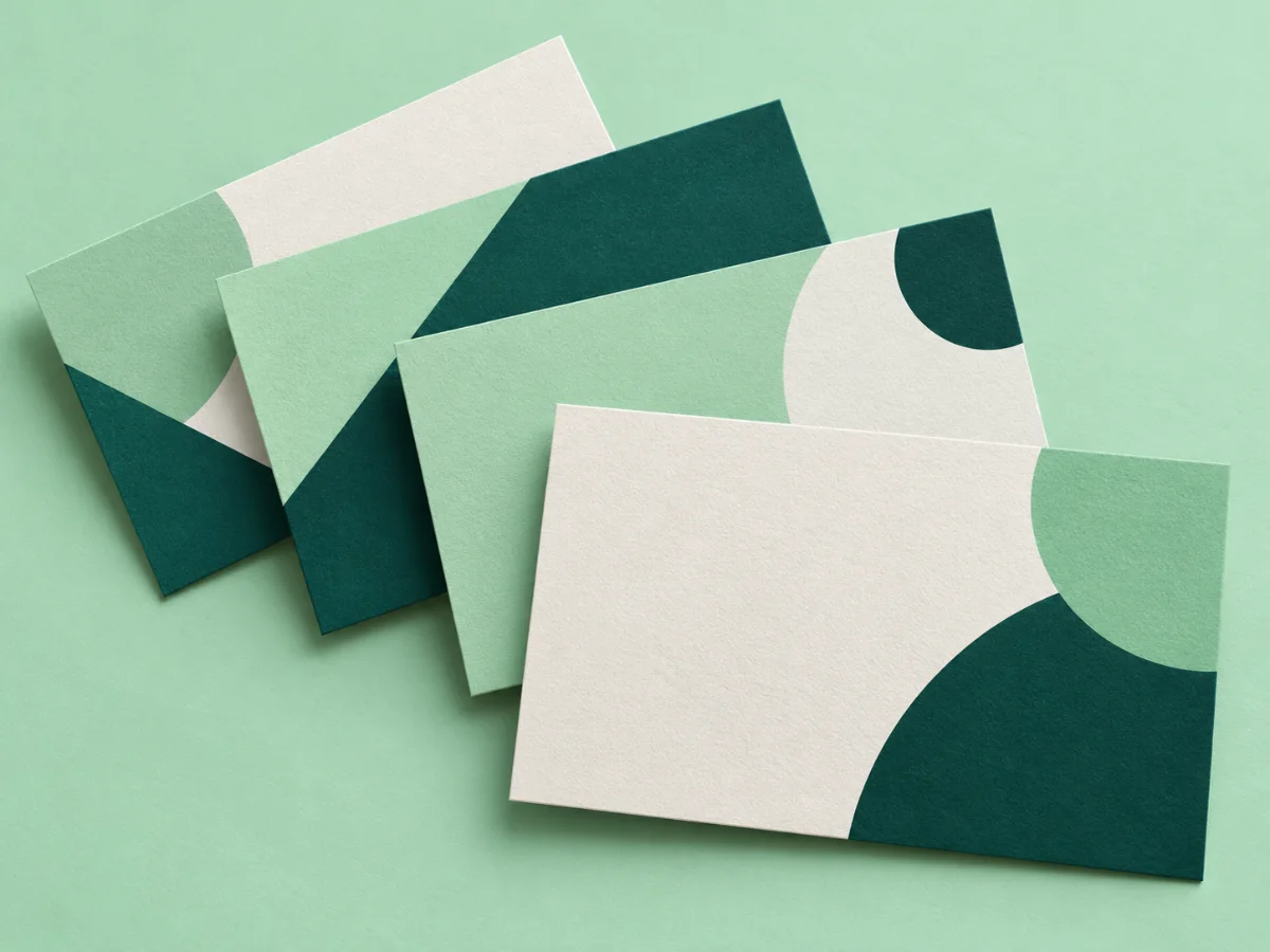 Fanned stack of premium visiting cards with abstract teal and mint designs on a mint surface